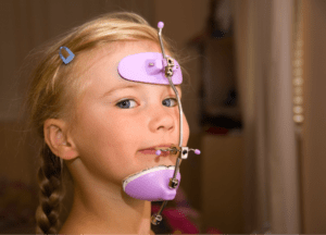 Young girl with blonde hair wearing orthodontic headgear