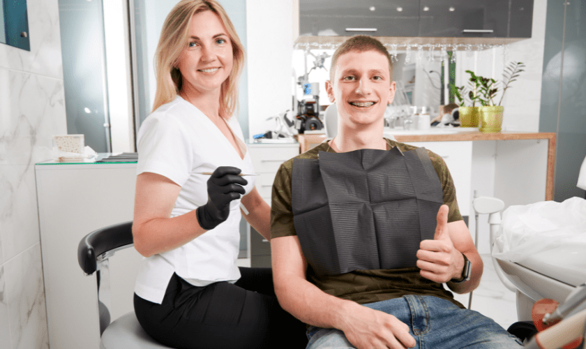 Orthodontist in white coat examining patient's teeth in modern dental clinic office.